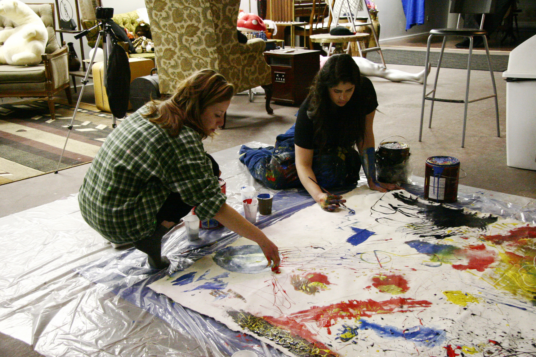 two artists crouched over a large floor painting