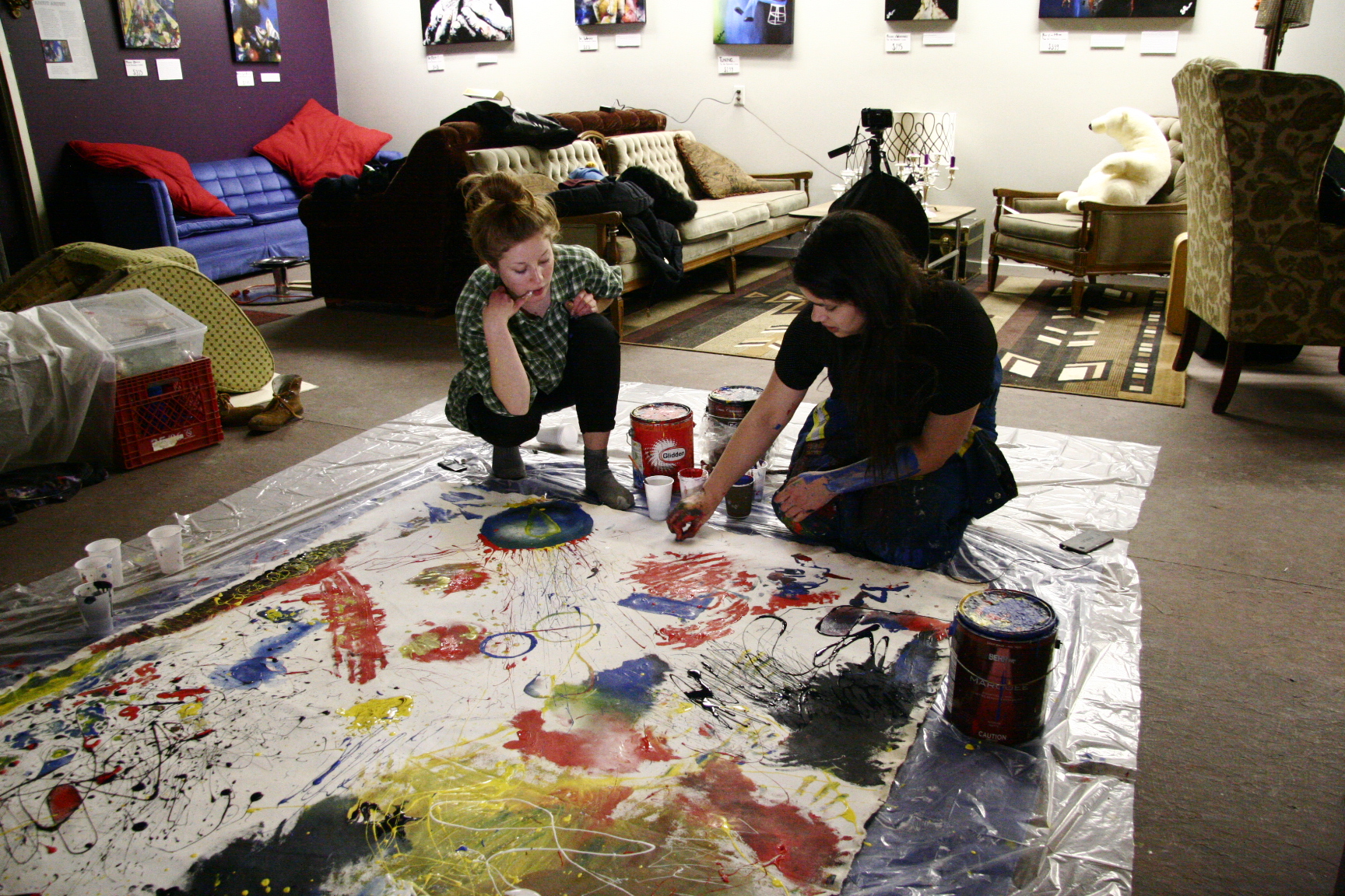 painting on the floor with art hung on the walls behind