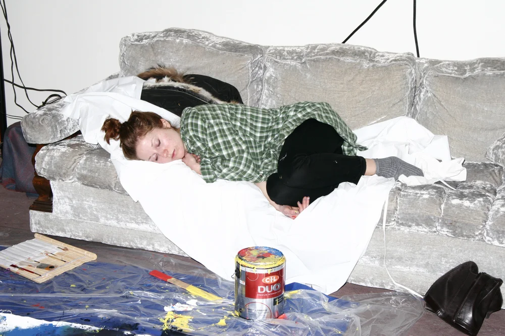 asleep on the gallery couch after a long night of painting